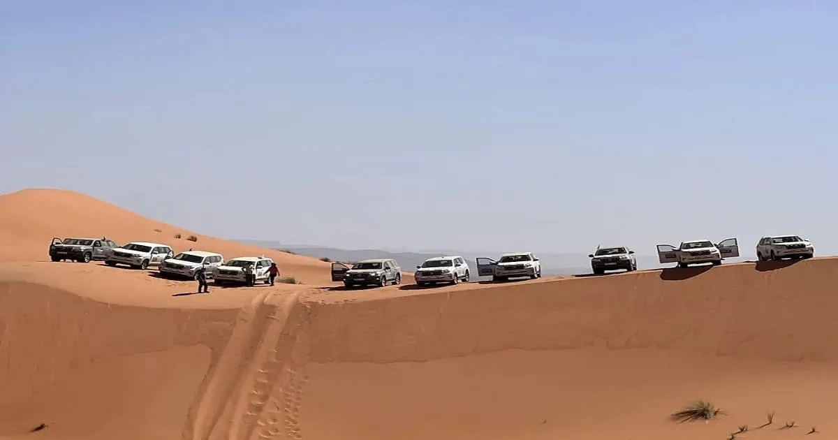 4x4 vehicle driving on desert road with sand dunes in background