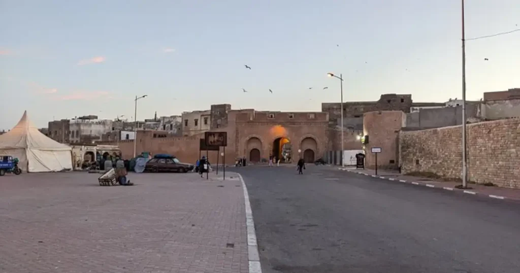 Entrance to Essaouira's main port parking lot with fishing harbor and medina walls in background